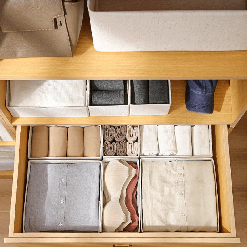 boites de rangement en coton et lin disposées sur étagère et tiroir ouvert avec vêtements pliés à l'intérieur