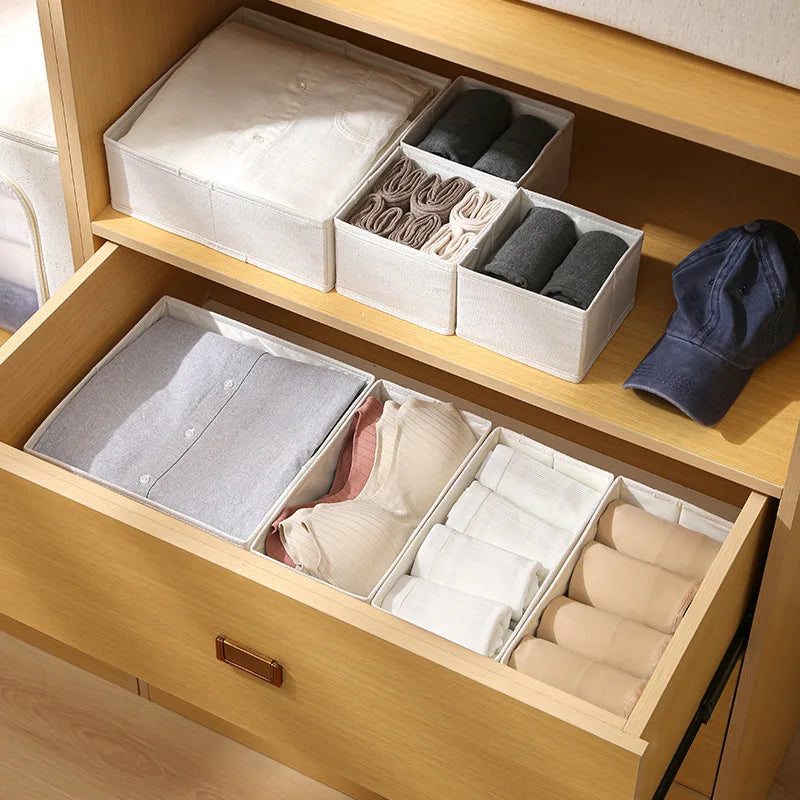 boites de rangement en coton et lin disposées sur une étagère et dans un tiroir avec vêtements pliés