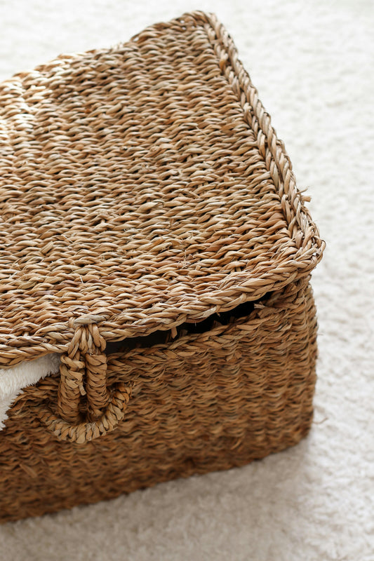 Panier malle en jonc de mer posé sur un tapis épais blanc