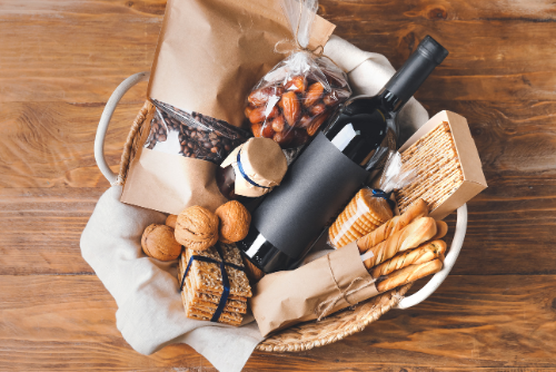 Paniers en osier garni d'une bouteille de vin, de gressins, de fruits secs et crackers