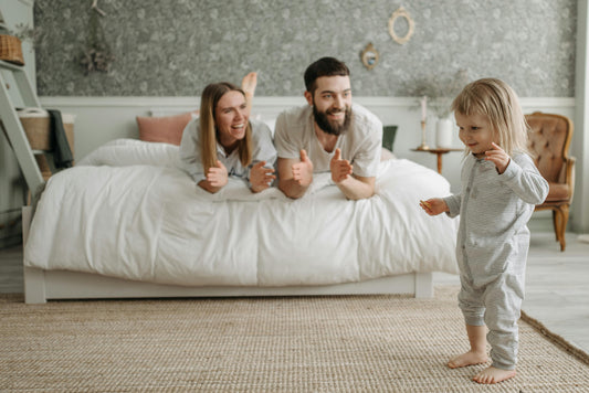 couple allongé sur un lit regardant un jeune enfant marcher