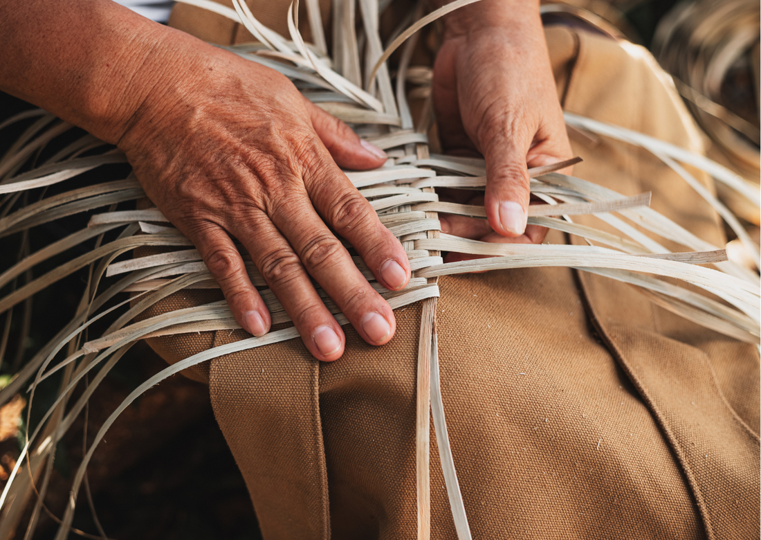 alt="Mains en train de tresser de l'osier pour fabriquer un panier artisanal"