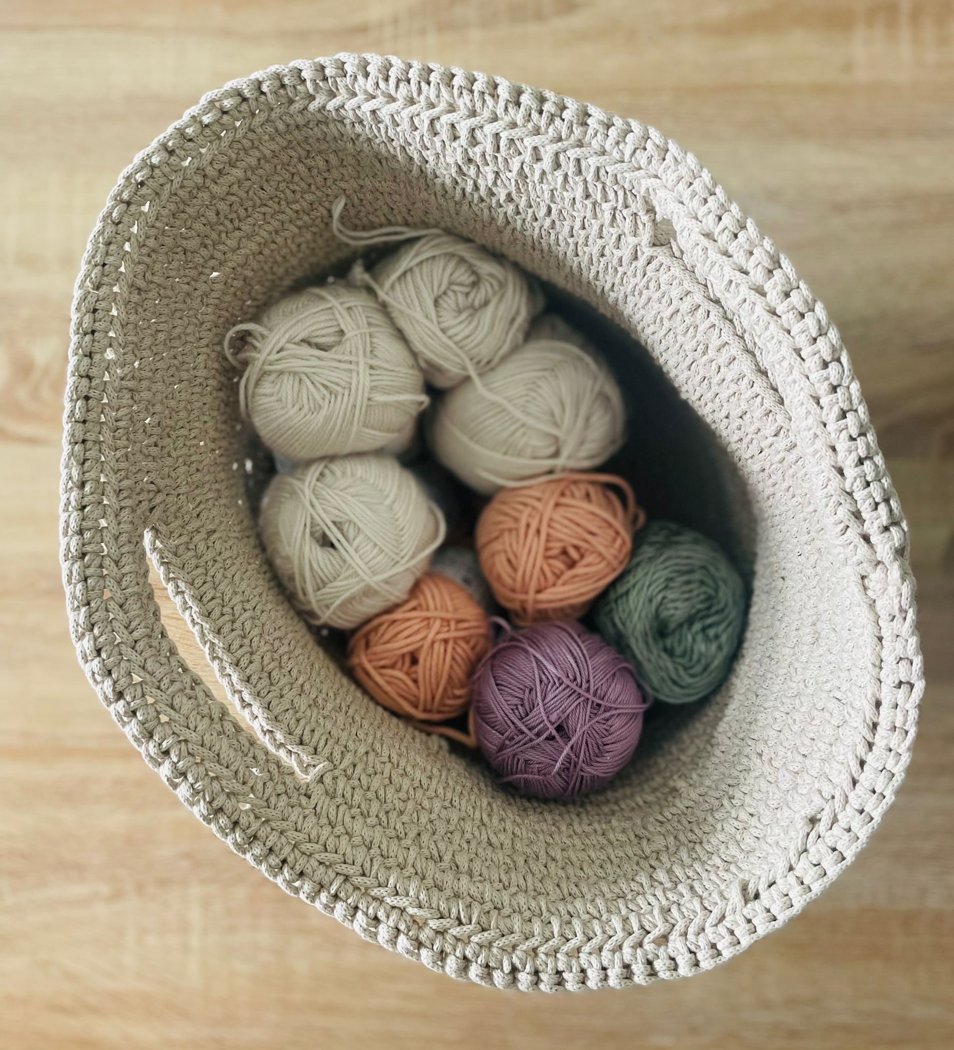 Panier en corde de coton couleur camel, contenant 8 pelotes de laine de couleurs différentes, beige rose violet vert
